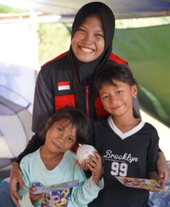 Relawan berhijab berfoto bersama dua anak perempuan