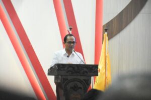 Pria berpidato di podium dengan bendera kuning