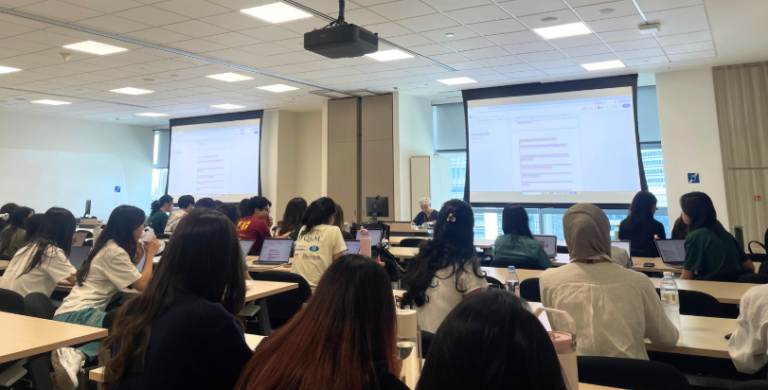Students attend a classroom presentation with projected slides.
