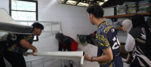 Students move furniture in a classroom with shelves