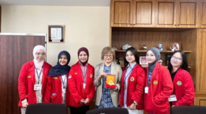 Students in red jackets present award to faculty member