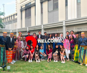 Diverse student group in traditional attire holding welcome sign
