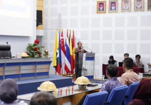 Speaker addresses audience beside international flags in conference hall