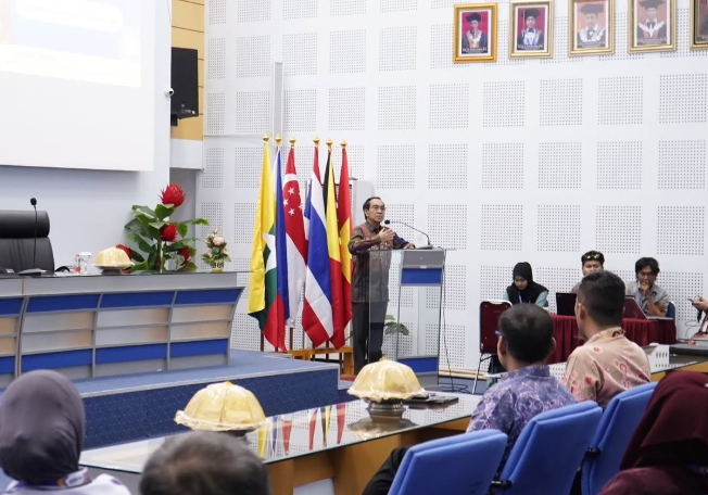 Speaker addresses audience beside international flags in conference hall