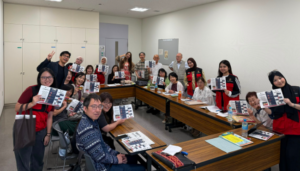 Classroom group proudly holds printed materials during a workshop.