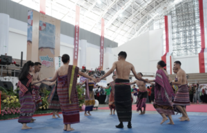 Traditional dancers perform in a circle at an indoor event