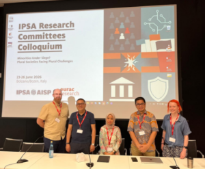 Five presenters stand before IPSA colloquium presentation slide.