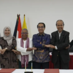 Seven officials link hands at a ceremonial signing table