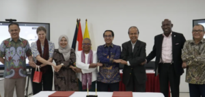 Seven officials link hands at a ceremonial signing table