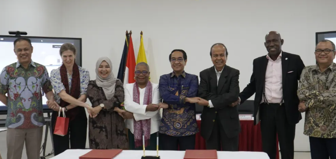 Seven officials link hands at a ceremonial signing table