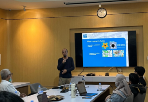 Presenter discusses research fields during a conference room meeting.