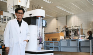 Scientist in lab coat beside industrial research equipment