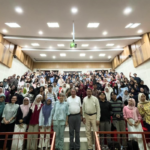 Large group posing in a modern lecture hall