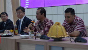 Officials in batik shirts speak at conference table