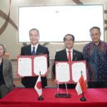 Officials display signed documents beside Japanese and Indonesian flags