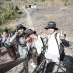 Four hikers pose on rocky hillside trail