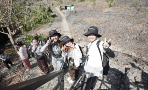 Four hikers pose on rocky hillside trail
