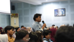 Student asks question with microphone in crowded lecture hall