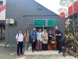 Seven people pose outside a gray building