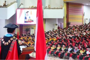 Rektor berpidato di wisuda dengan bendera Indonesia