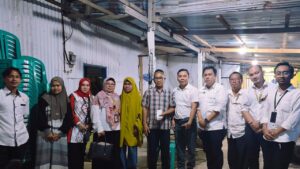 Sekelompok warga dan petugas berfoto di ruangan sederhana