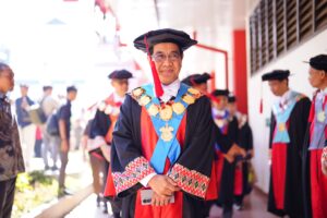 Rektor berbusana wisuda berdiri di antara akademisi