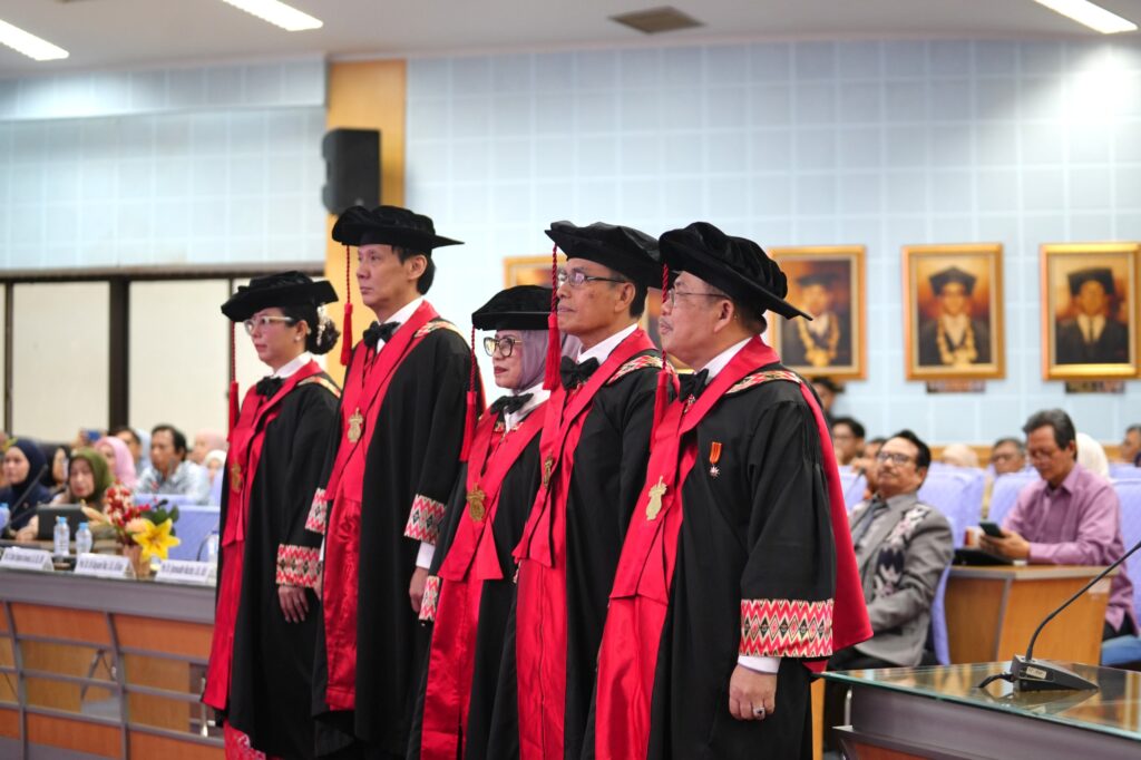 Lima akademisi berdiri mengenakan toga hitam merah