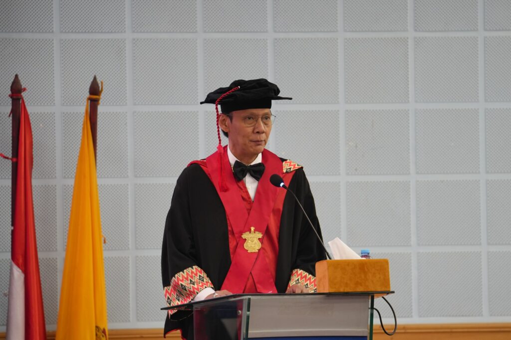 Pria berjubah akademik berpidato di podium