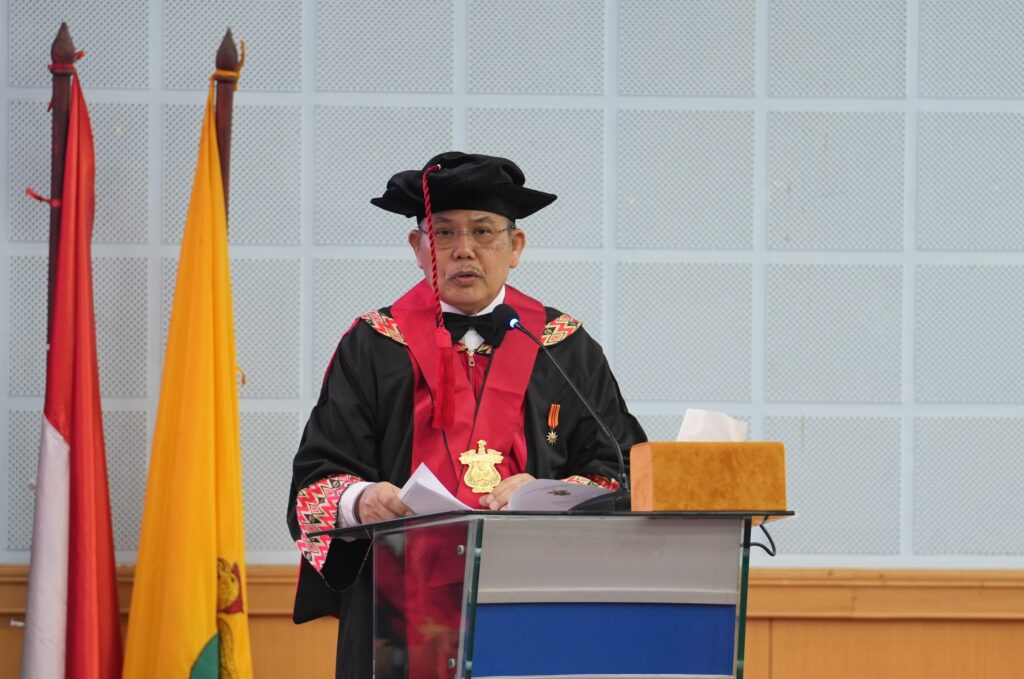 Pria berjubah akademik berpidato di podium