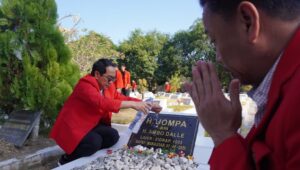 Pria berbaju merah berdoa di makam