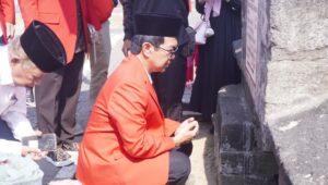 Pria berjas merah berdoa di depan makam