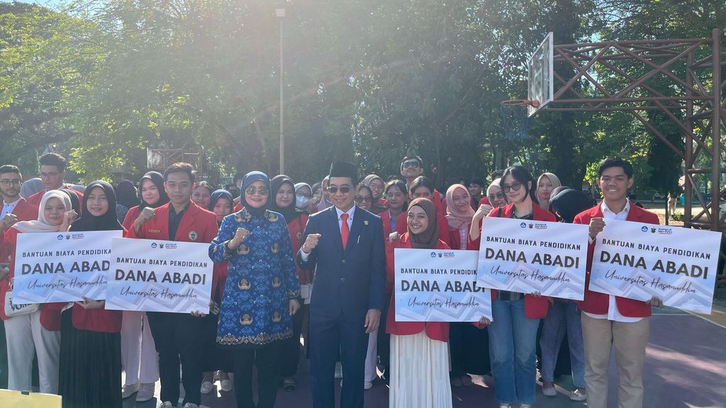 Hasanuddin University students hold Dana Abadi education grant signs.