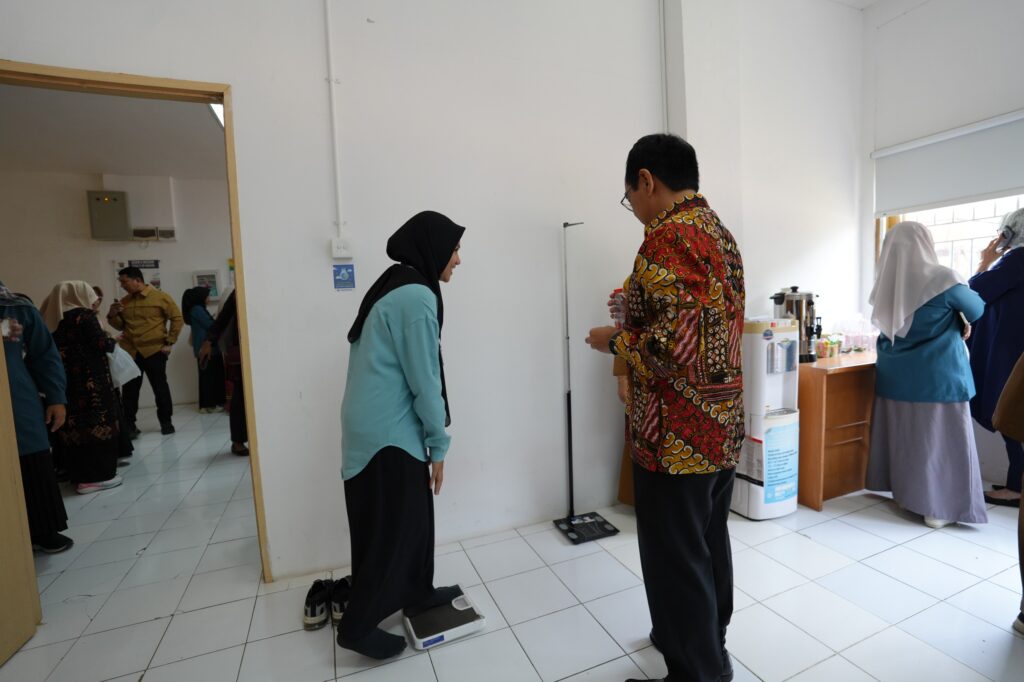 Perempuan berhijab menimbang berat badan di ruang kesehatan