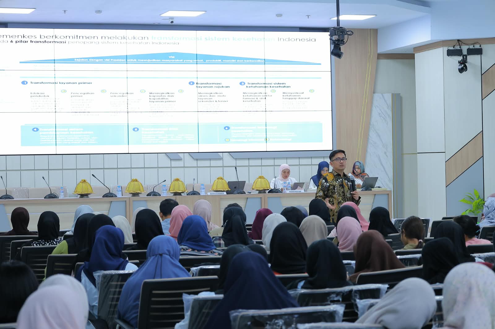Presentasi transformasi kesehatan di depan peserta seminar