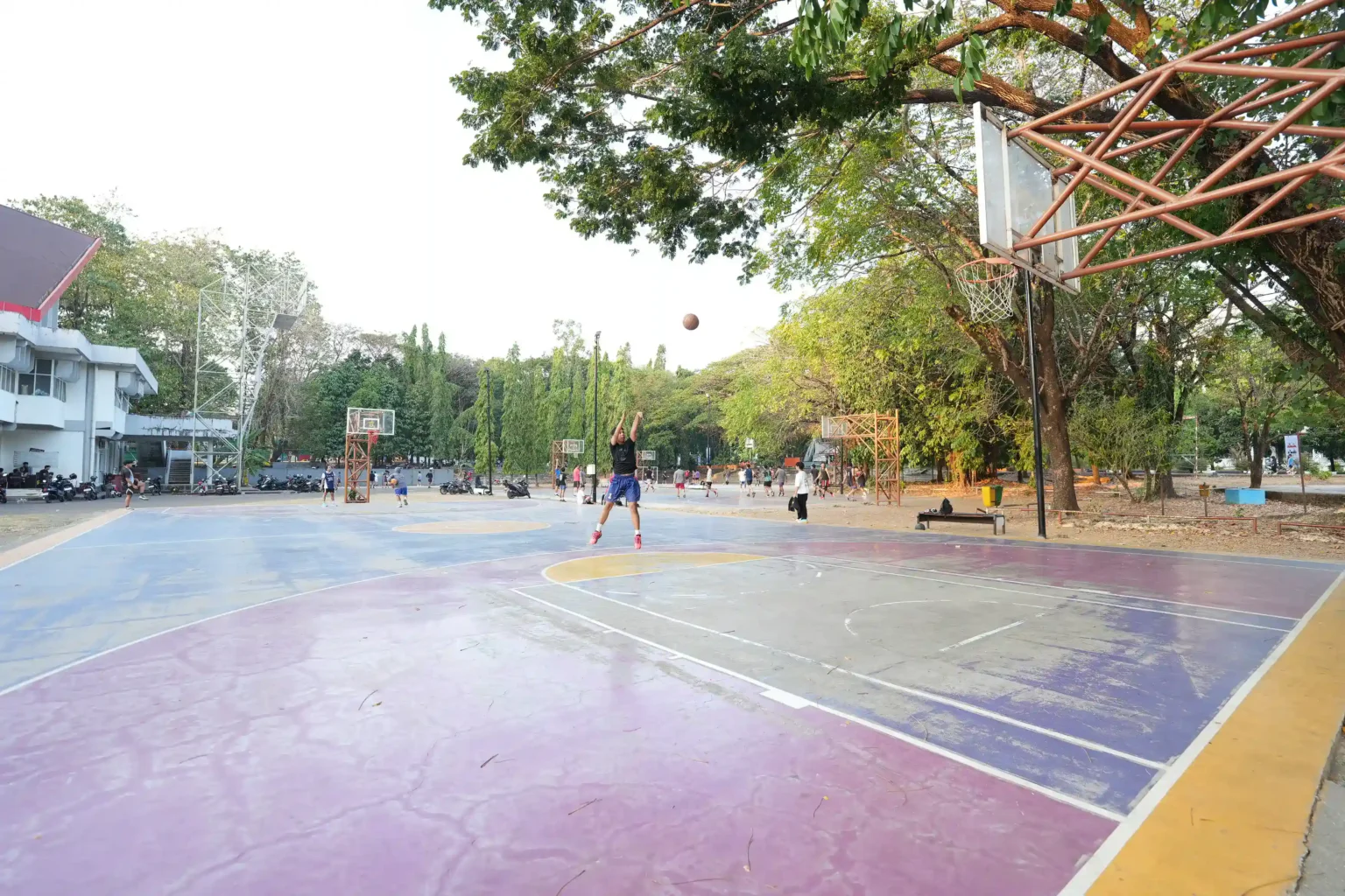 Pemain basket menembak bola di lapangan luar ruangan