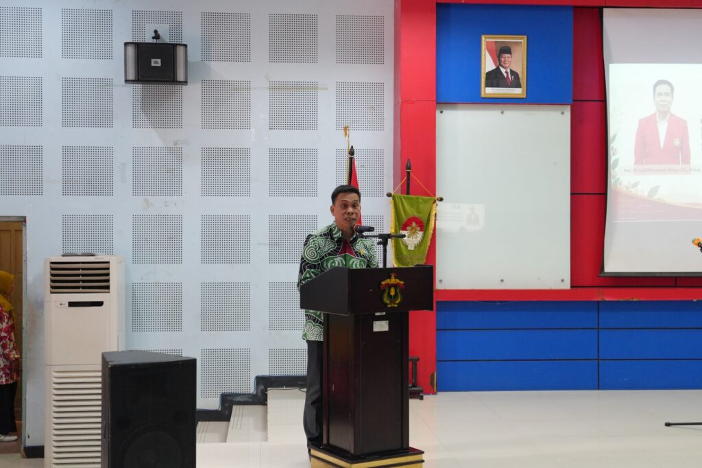 Pria berbatik berpidato di podium aula