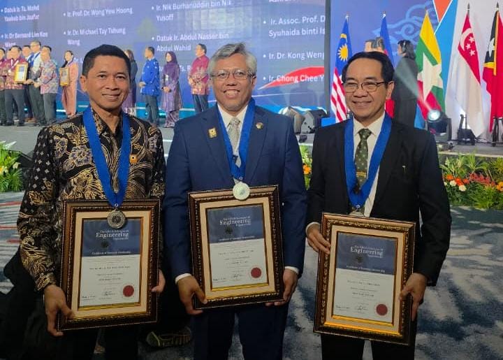 Tiga penerima penghargaan memegang sertifikat berbingkai di panggung