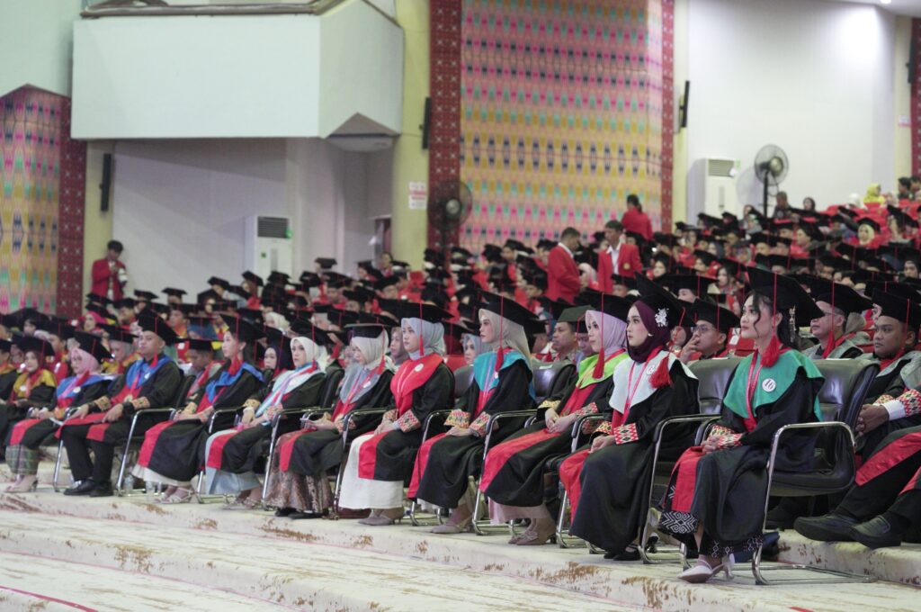 Para wisudawan duduk di aula saat upacara kelulusan