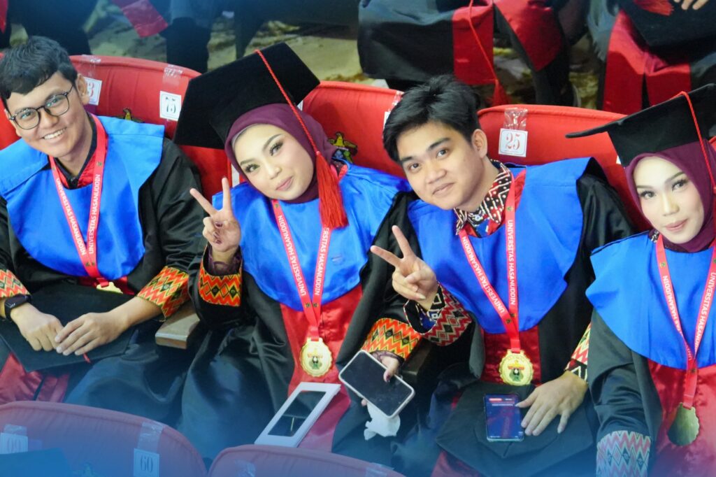 Empat wisudawan berpose di kursi auditorium